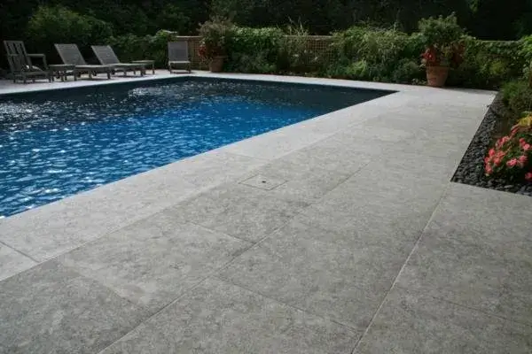 Large Limestone Tiles on Pool Deck The textured limestone is the ideal material for this pool deck due to the slip resistance and its ability to remain a cooler temperature in the southern summer sun.